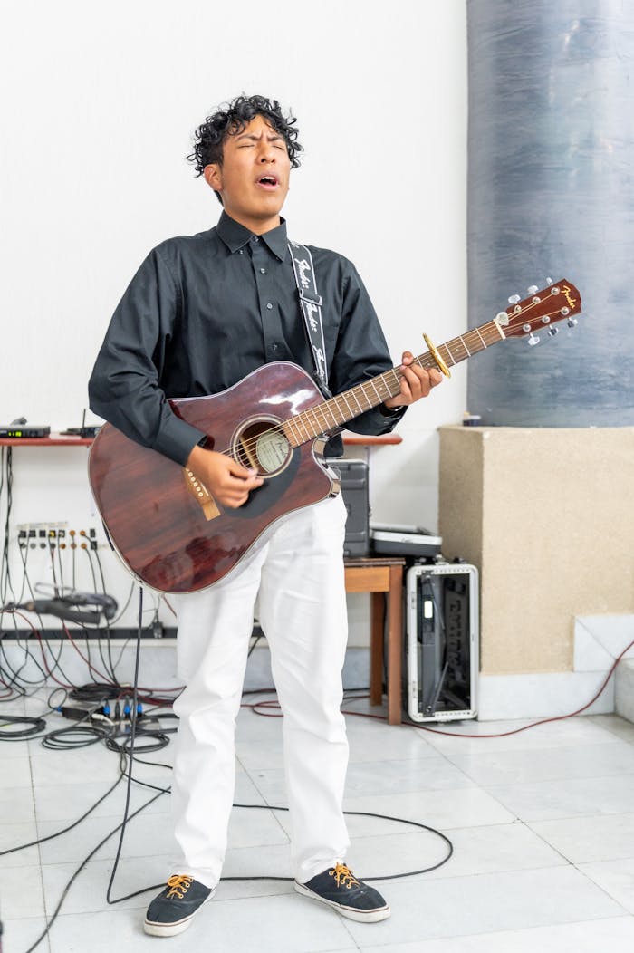 A young male musician passionately plays acoustic guitar indoors in Mexico City.