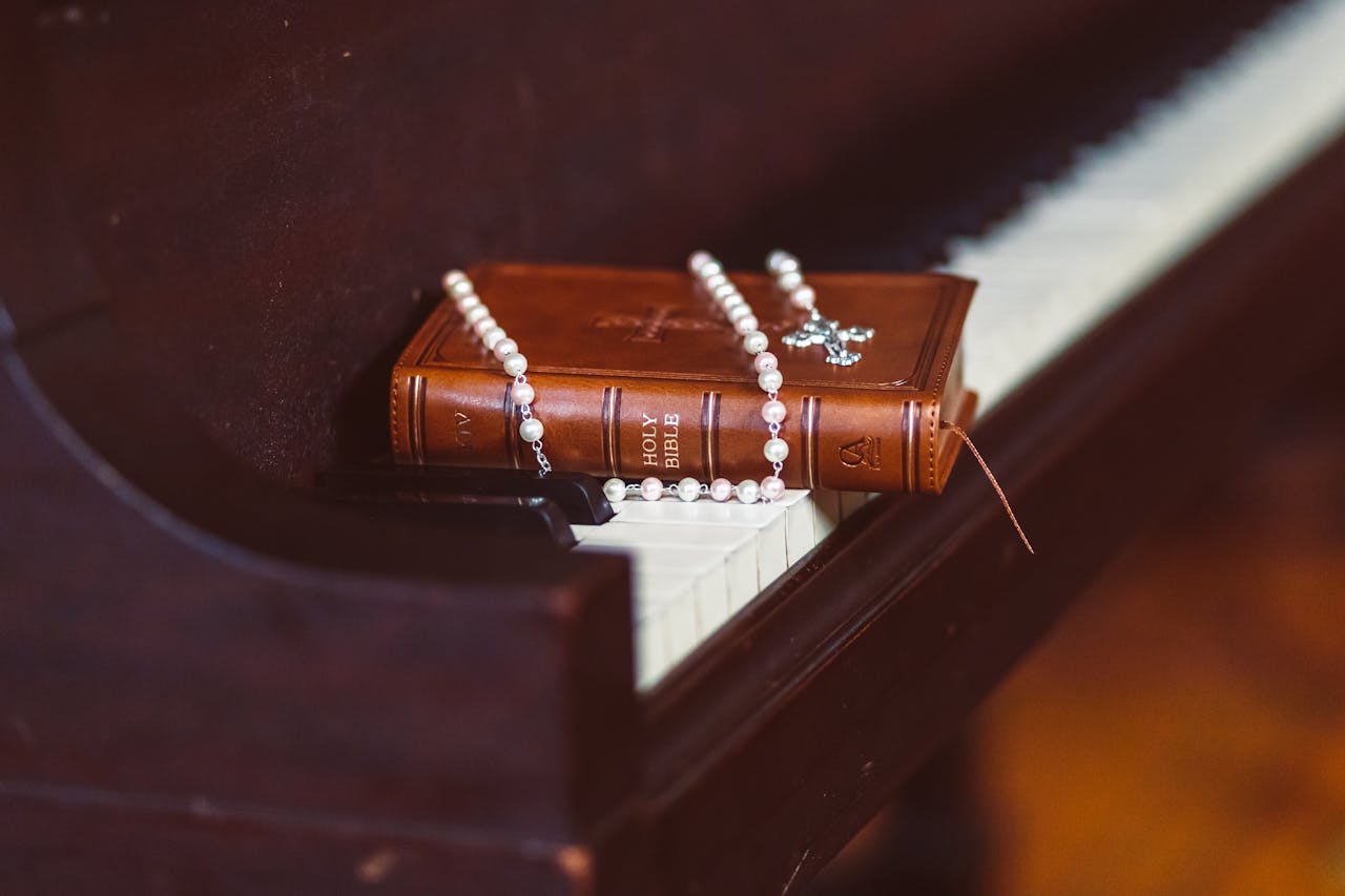 A Bible and rosary resting on a piano, symbolizing faith and music harmony.