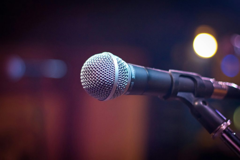 Home Dynamic microphone on stand with blurred stage lights in background.